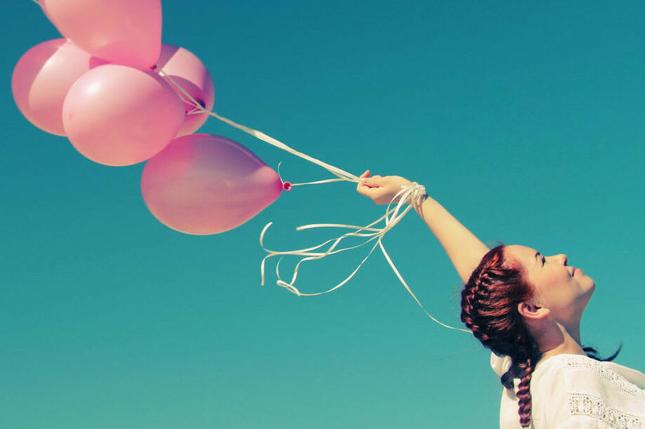 Femme tenant des ballons à l’hélium, illustrant la libération et le contrôle retrouvé après un accompagnement en hypnose pour compulsions et dépendances à Noyal-Châtillon-sur-Seiche
