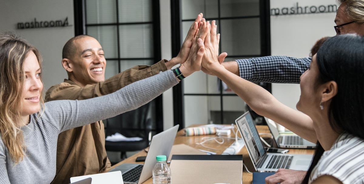 Cohésion d’équipe et bien-être en entreprise grâce à l’hypnose Photo de collaborateurs en entreprise, assis autour d’une table, joignant leurs mains au centre pour symboliser la cohésion et la solidarité.